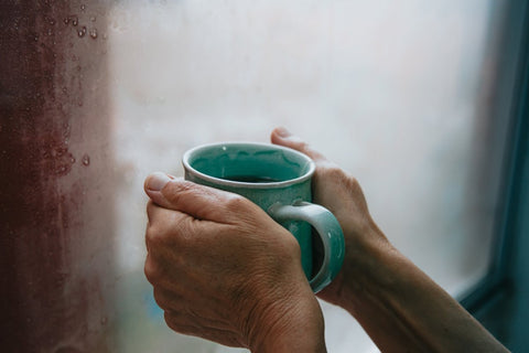 A mug of tea being held by a window